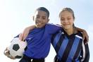 2 children, black boy on left and white girl on right arm and arm with soccer ball