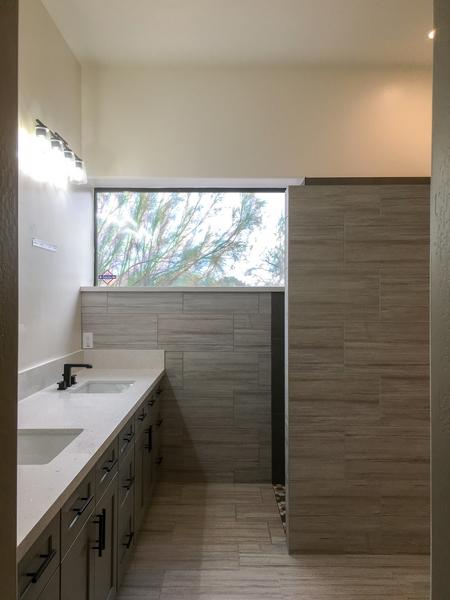 Master bathroom with a large His and Her gray sink vanity and white marble counter. A large walk-in tiled shower.