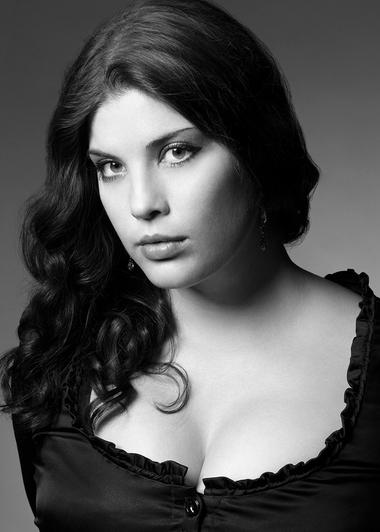 Black and white photo of spinto soprano Megan Marie Hart with her hair curled and draped over her right shoulder.