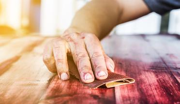 a hard worker refinishing furniture with the necessary tools