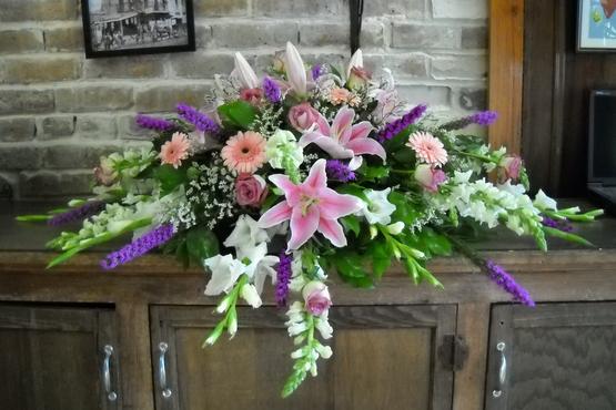 Spray in blush, lavender, purple, and white with gerbera daisies, stargazers, snap dragons, gladioli, roses, and filler