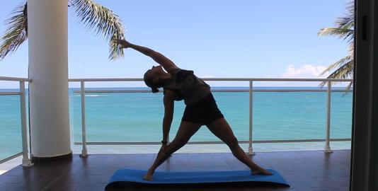Yoga teacher practicing torso stretching poses for Flexibility in a balcony in front of the. Ocean front stretching exercises for the improvement of overall body flexibility.