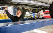 mechanic performing repair work under elevated vehicle