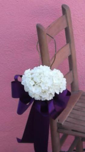 Head of white hydrangea hanging of a chair with a ribbon flowing beneath it