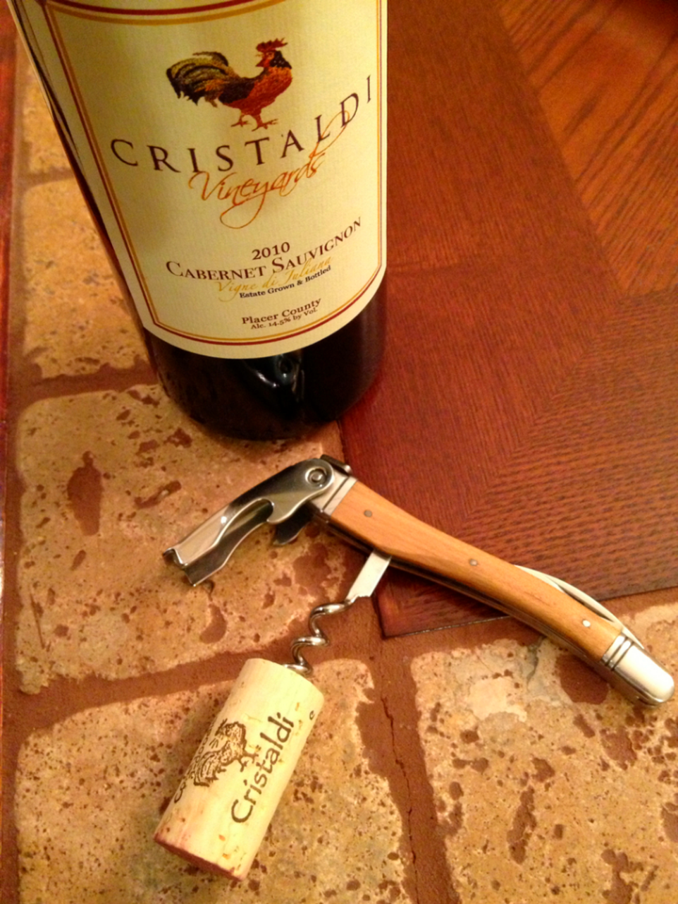 Photo of a bottle of Wine with corkscrew set on table