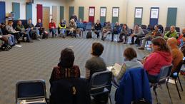 People sitting around in a circle listening to a group session.