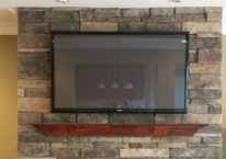 Flat screen tv mounted on stone fireplace