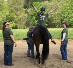 Colby's Army photo of Cindy Johnson in a therapeutic riding lesson with child participant and bay horse