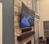 Curved flat screen tv mounted over fireplace, sound bar floating under TV. Carolina Custom Mounts