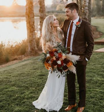 Getting married in Oregon under arch with red flowers.