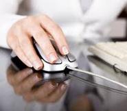 Right hand holding a computer mouse next to a computer keyboard.