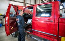 diesel mechanic inspecting interior driver's side of red truck