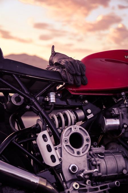 motorcycle gloves over cafe racer motorcycle sunset