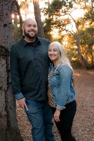 couple portrait in the forest with man leaning up against tree and wife next to him in jean jacket by Monterey Bay couples photographer