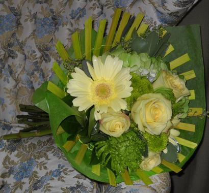 Paper wrapped bouquet with light yellow gerbera daisy and roses with green hydrangea, poms, and fuji mums
