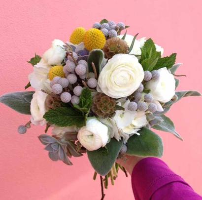 Hand-tied bridal bouquet with white ranunculus, brunia, billy balls, succulents, and other elements