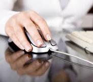 Close up of a man using a computer mouse next to a computer keyboard.