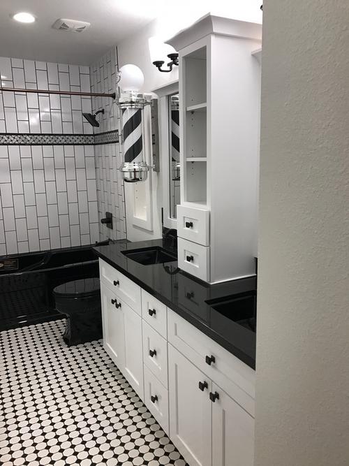 Jack Daniels themed bathroom with the color of the tile, cabinets, counters, toilet, and tub all being either black or white.