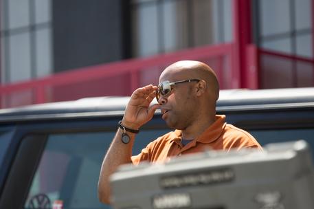 black male outside holding sunglasses on face