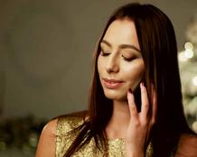 Young white woman with dark black straight hair holding a phone to her left ear as she listens to the person on the other end.