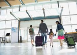 Parents with children pulling suitcases as they are leaving airport