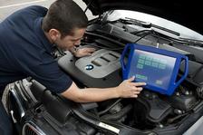 Auto technician looks up information on a tablet while working on a vehicle
