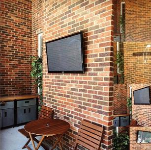 Flat screen television installed on brick wall on a patio. power and HDMI installed by carolina custom mounts in charlotte nc