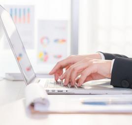 Woman's hands stretched forward as she types on laptop.