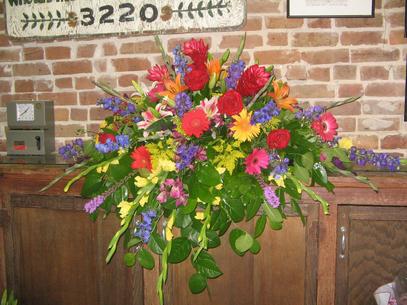 Large spray done in jewel tones, including ginger, roses gerbera daisies, delphinium, lilies, liatris, berries, and orchids