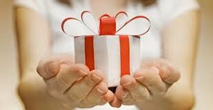 Young woman holding a white gift box with a red ribbon in palm of her stretched out hands.