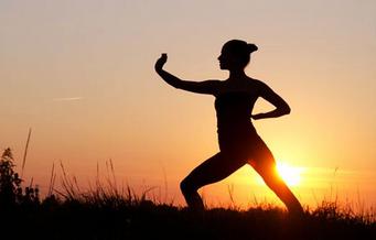 Student practicing Chi Gong exercises in front a sunset