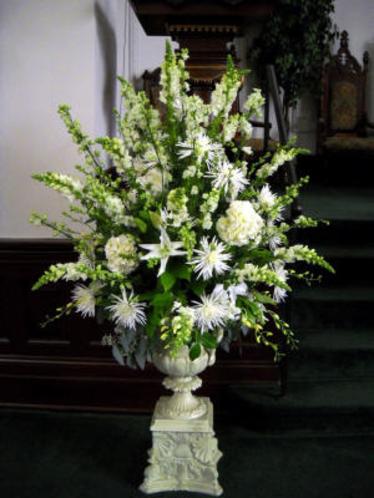White and green flowers arranged tall in a large urn including casa blancas, hydrangea, snap dragons, fuji mums, and orchids