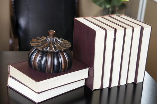 Picture of two books stacked on sides topped with a decorative holder with six books standing to the right.