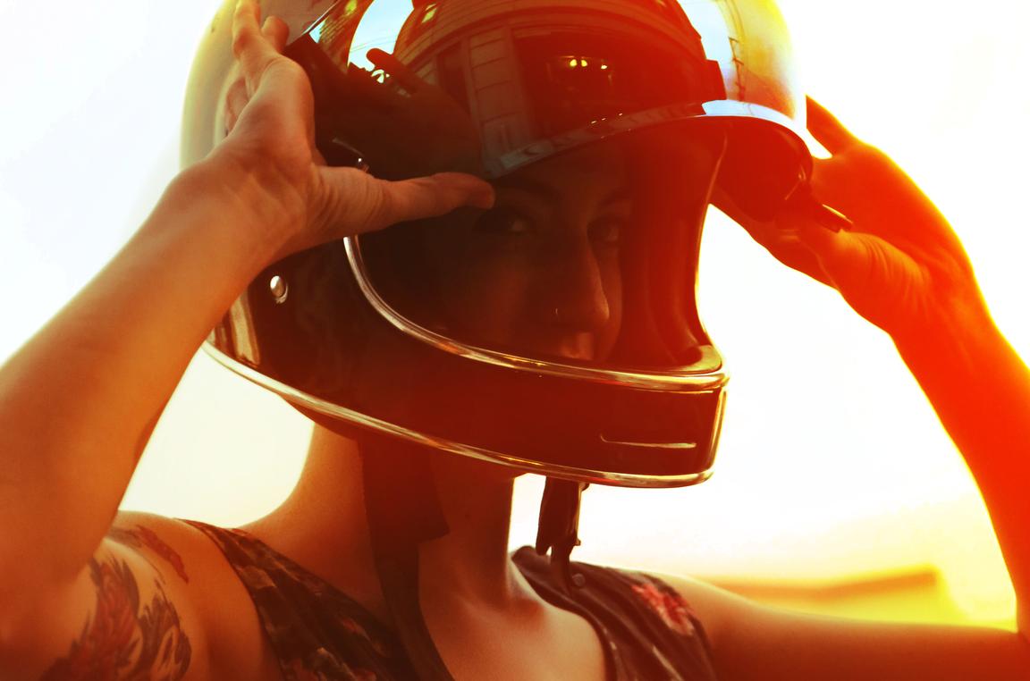 young biker woman with helmet lifestyle orange sunset high exposure