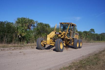 CAT motorgrader grading a dirt road in rural Florida