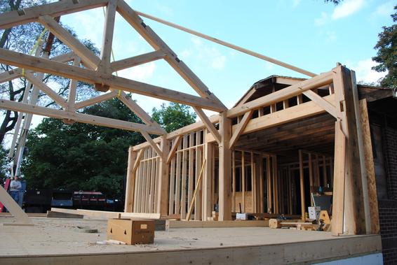 Timber frame addition being raised next to existing home.