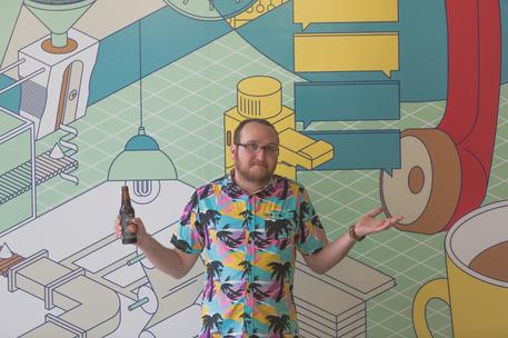 young man in hawaian shirt in front of tech mural