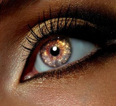 Close up view of a woman's gold shimmering eye looking into the distance