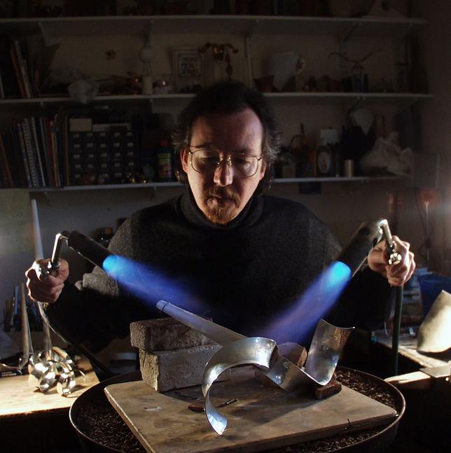 Kevin O'Dwyer in his workshop soldering a silver candlestick.