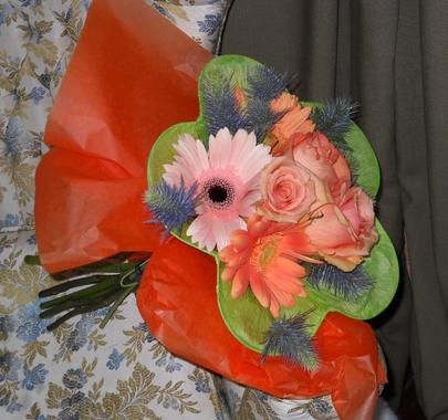 Paper wrapped bouquet with blush and peach gerbera daisies, blue thistle, and peach roses