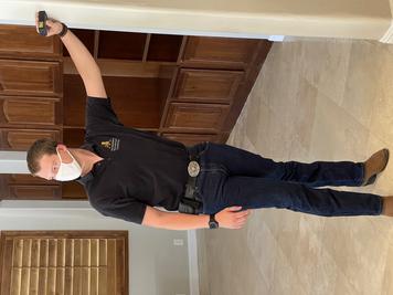 Picture of Garrett Helmandollar (Shad Helmandollar's son) is wearing a white mask, HRC polo shirt, Jeans, Belt with a silver Belt Buckle, and Cowboy Boots. He is holding a handheld laser tape-measure and is gathering measurements to render and plan a new project.