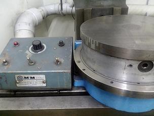 An older continuously rotating rotary grinding table sitting in a corner of cnc milling shop