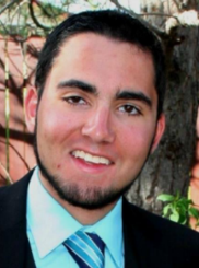 Picture of Tony smiling at camera wearing a sport coat and tie.