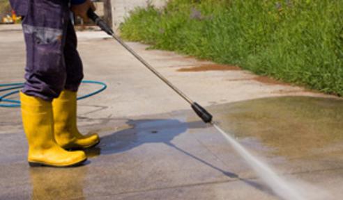 handy man using a pressure washer on a driveway