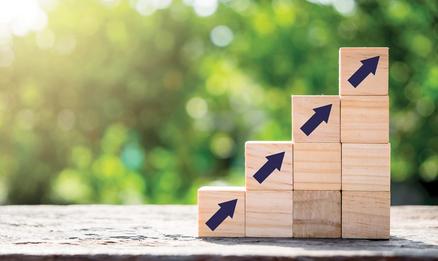 Stacked wooden blocks with blue arrows shoring growth with a natural green background