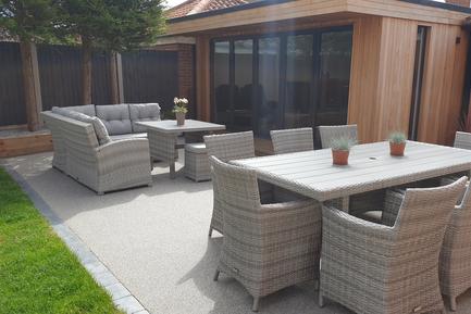 Modern garden room with 5 panel bifold doors and full length side window, next to a patio with tables and chairs