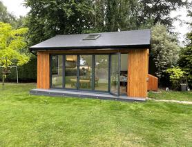 Cedar clad garden room with pitched roof and 5 panel bifold doors