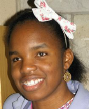Portrait picture of Quinita, smiling and looking at the camera with bow in her hair.
