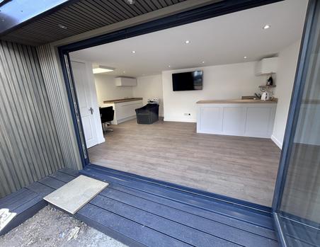 Garden hair salon with beige slatted cladding and open 3 panel bifold doors