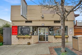 Photo of the exterior 45 Visitacion Ave, Brisbane, CA. Small, tan-colored deli style building with a tree in front.